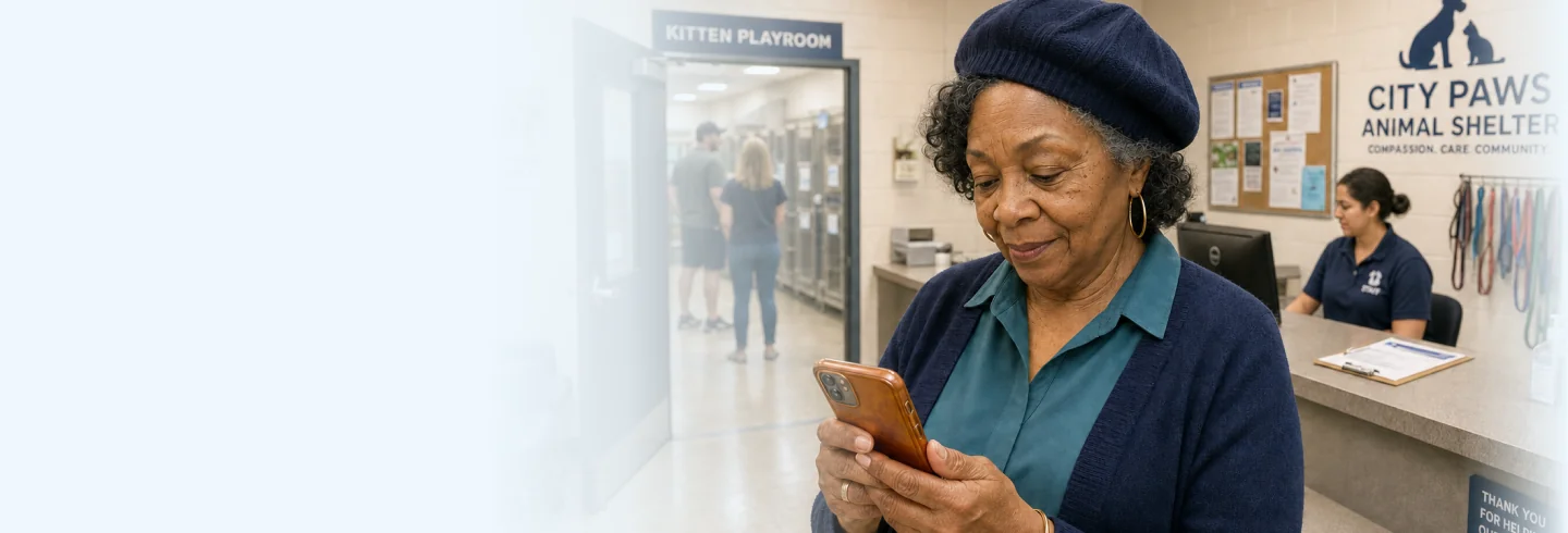 An adopter smiling at a Shelterpay checkout on her phone in a shelter lobby